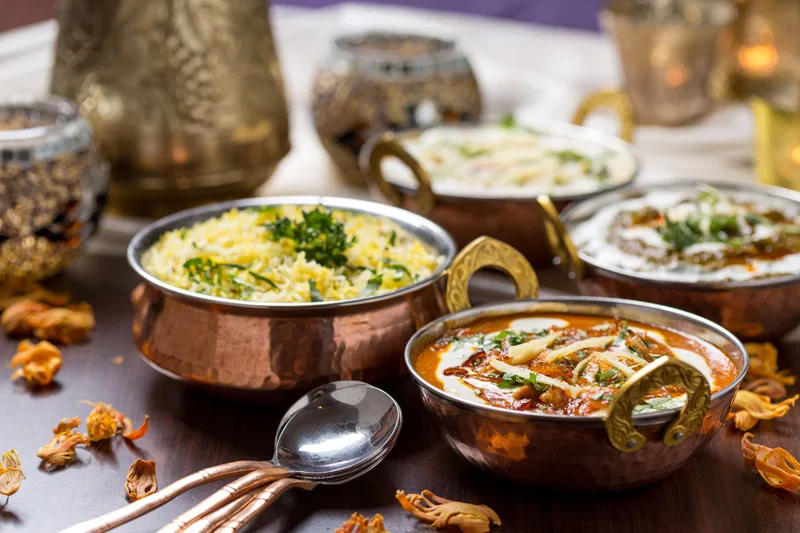 Indian curries and rice served in traditional copper bowls